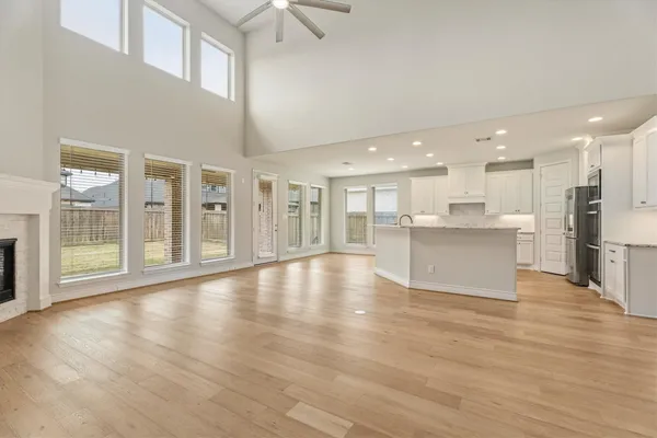a view of an empty room with wooden floor and a kitchen