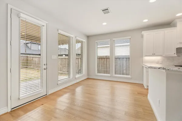 a view of an empty room with a window and wooden floor