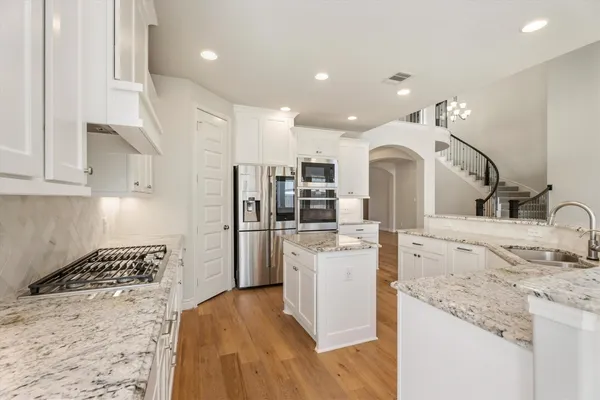 a large kitchen with stainless steel appliances kitchen island granite countertop a refrigerator and a stove top oven