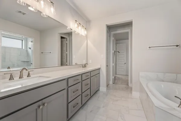 a spacious bathroom with a granite countertop sink mirror and a bathtub