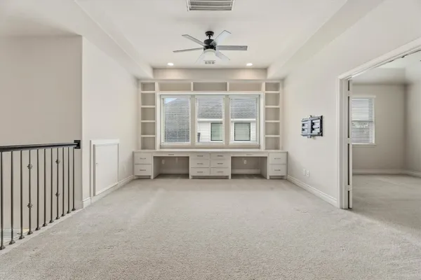 an empty room with windows and ceiling fan