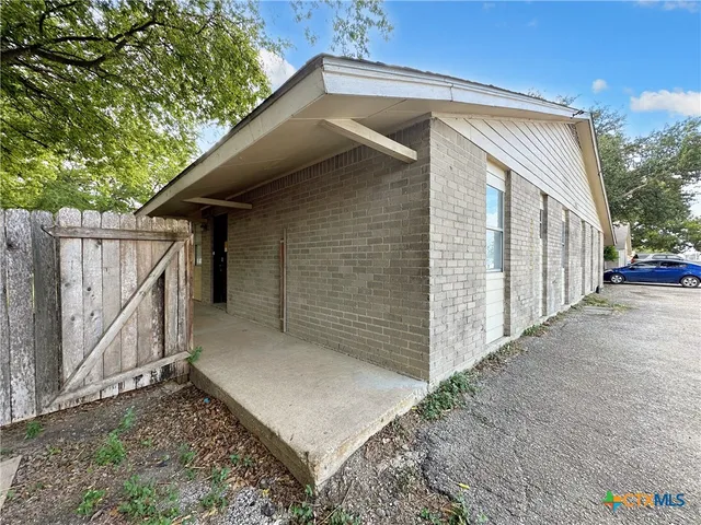 a view of a house with a small yard and wooden fence