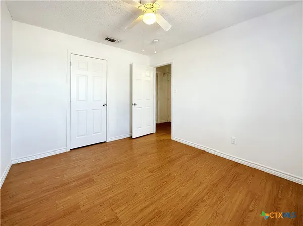 a view of an empty room with a chandelier fan