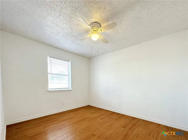 an empty room with a window and a ceiling fan