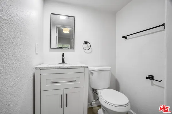 a bathroom with a toilet sink vanity and mirror