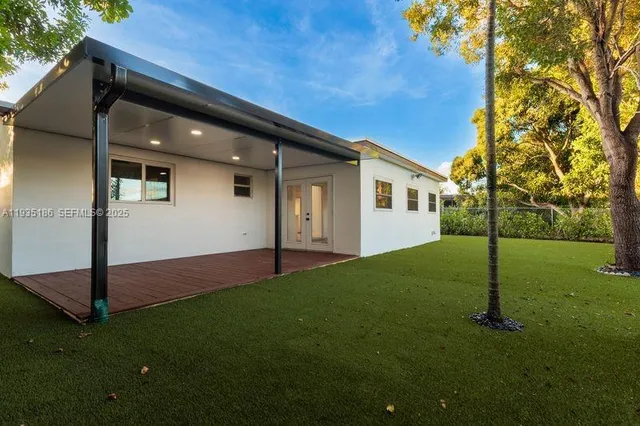 a backyard of a house with plants and large tree