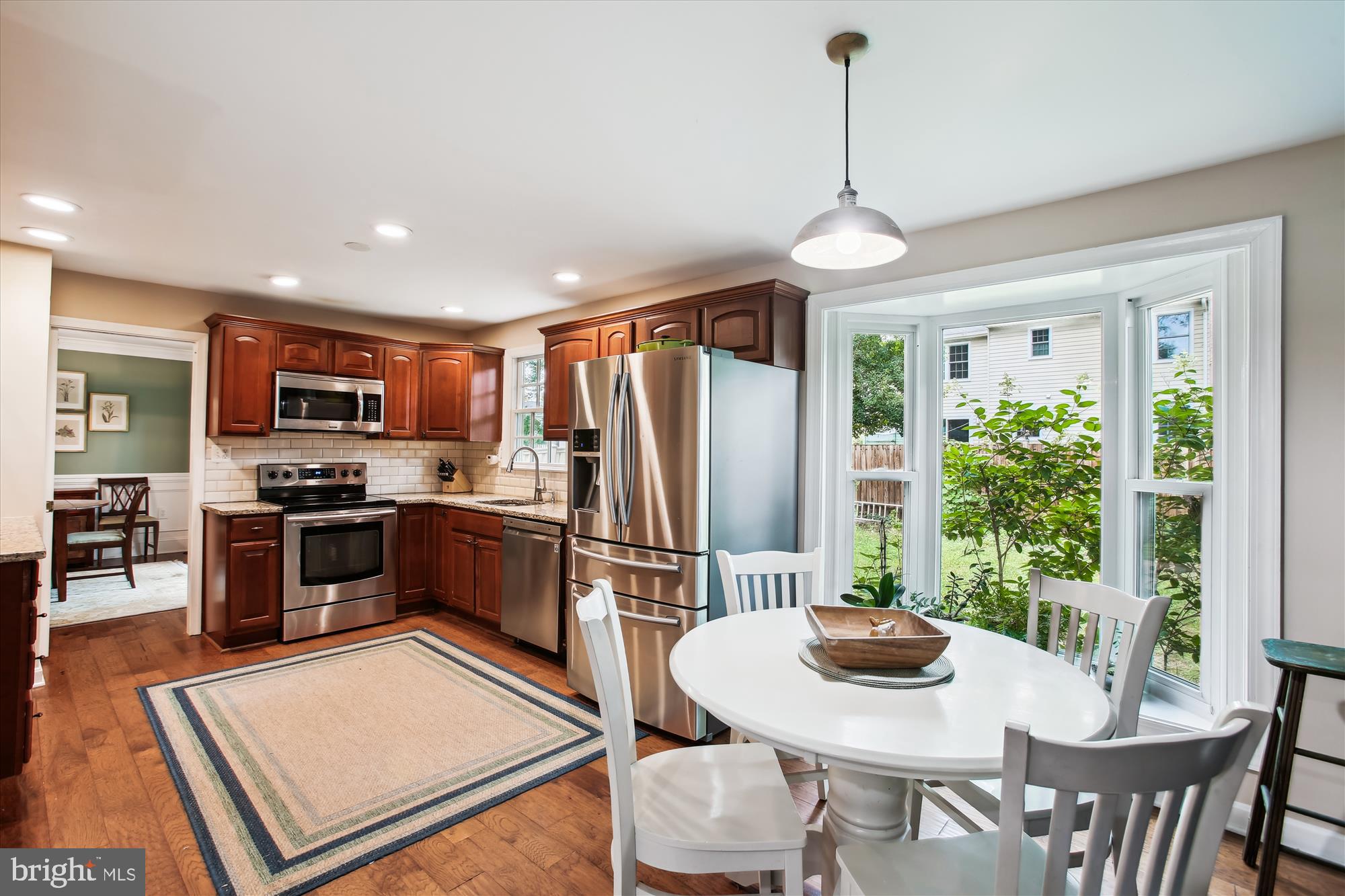 8231 Crown Court Road Alexandria, VA 22308 - Photo 8 of 33 a kitchen with stainless steel appliances granite countertop a stove a refrigerator a sink dishwasher a dining table and chairs with wooden floor