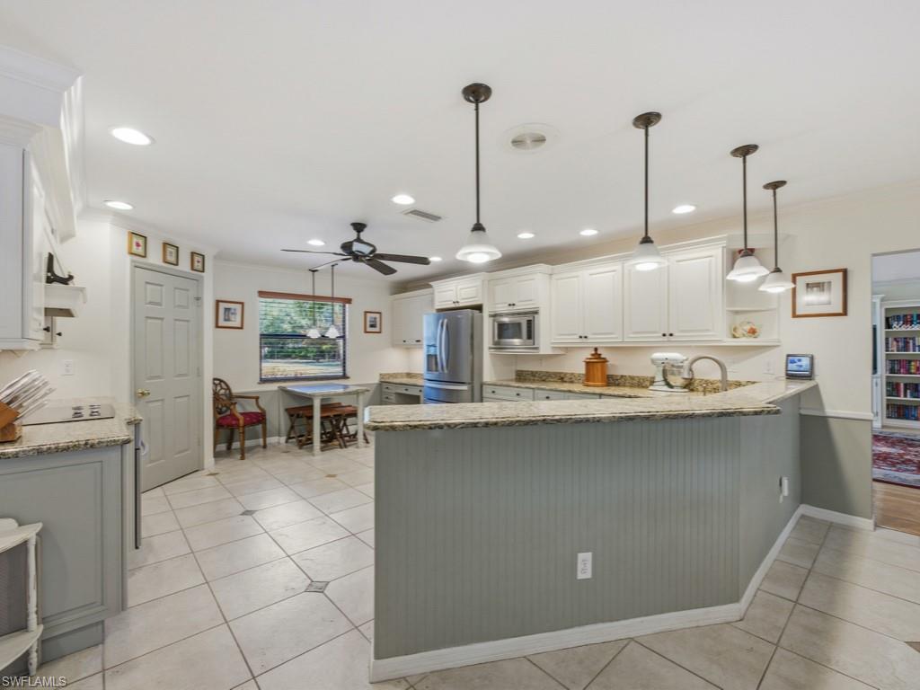 6840 Sable Ridge Lane Naples, FL 34109 - Photo 17 of 38 Kitchen with hanging light fixtures, light stone countertops, a peninsula, and ornamental molding
