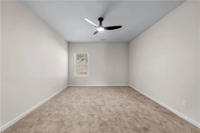 an empty room with a ceiling fan and window