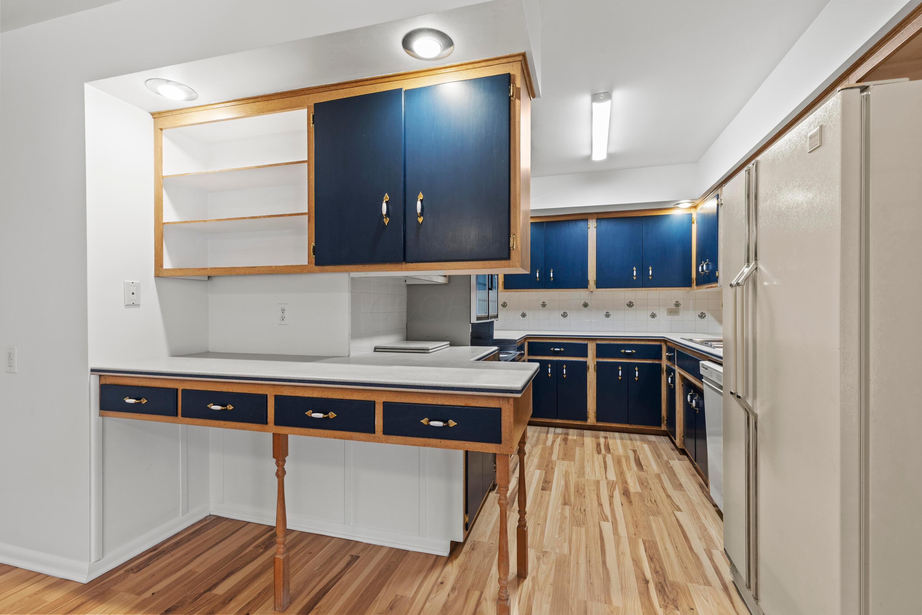 6982 Lee Road Westerville, OH 43081 - Photo 21 of 71 • New neutral vinyl flooring ~ 2020/2021 • White painted walls • Corian countertops • Kenmore® electric range (disconnected) • Blue cabinets • KitchenAid® dishwasher • Triple bowl, stainless steel sink with sprayer • Ceramic tile backsplash • Microwave • Whirlpool® refrigerator
