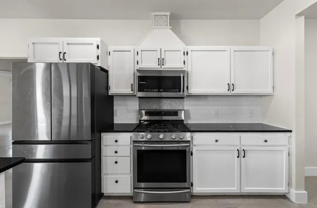 a kitchen with stainless steel appliances granite countertop a sink and a white cabinets