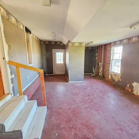 a view of an empty room with window and stairs