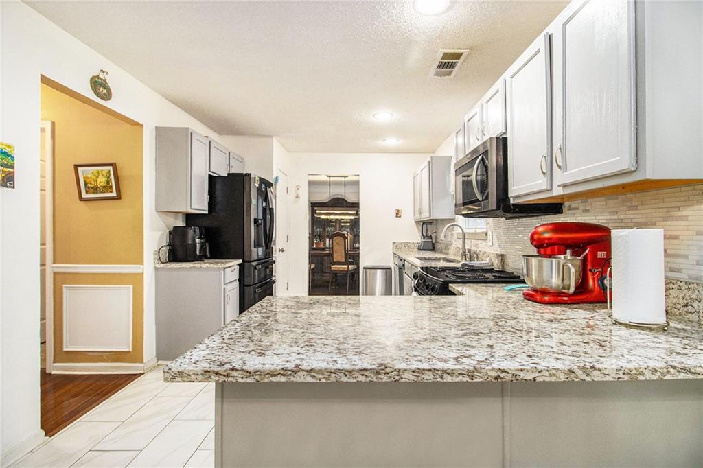 5139 Miller Woods Trail Decatur, GA 30035 - Photo 16 of 36 a kitchen with stainless steel appliances granite countertop a sink refrigerator and cabinets
