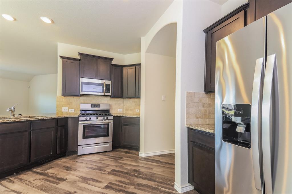 574 Kara Drive Fate, TX 75087 - Photo 7 of 15 a kitchen with stainless steel appliances granite countertop a refrigerator and a stove top oven