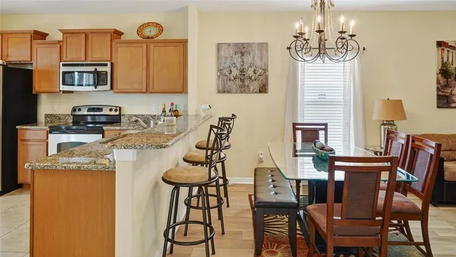 a kitchen with stainless steel appliances granite countertop a table and chairs in it