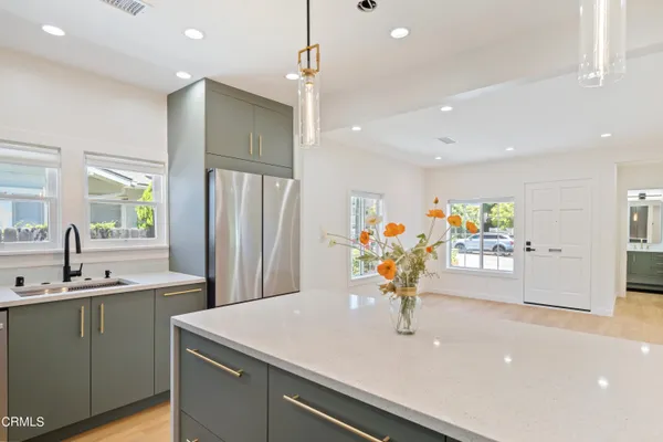 a kitchen with stainless steel appliances a sink dishwasher a refrigerator and a dining table with wooden floor