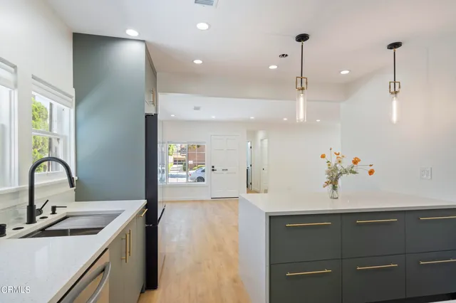 a kitchen with kitchen island stainless steel appliances a sink and a wooden floor