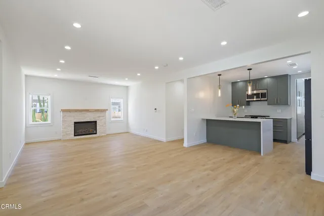a view of an empty room with a kitchen and a window