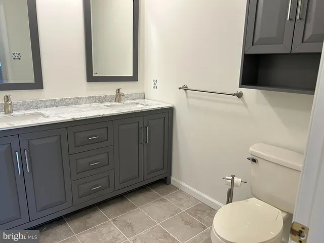 a bathroom with a granite countertop toilet sink and mirror