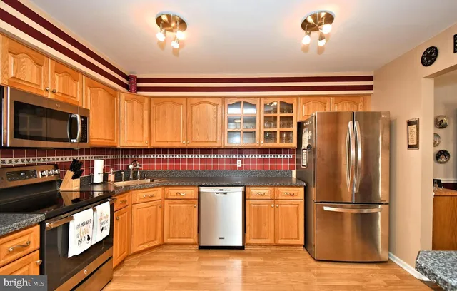 a kitchen with stainless steel appliances granite countertop a refrigerator a stove and a sink with wooden floor
