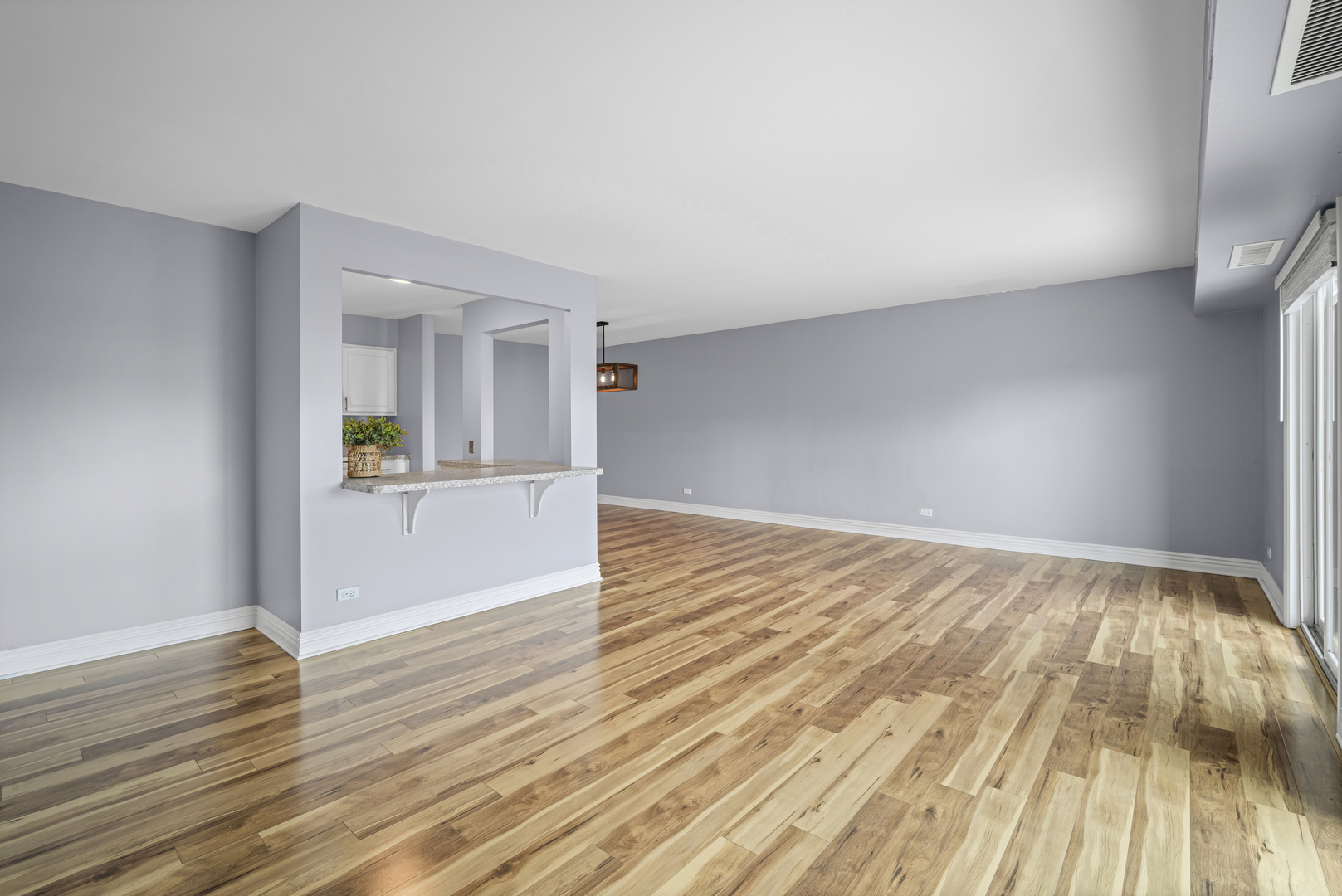 1615 East Central Road, Unit 417C Arlington Heights, IL 60005 - Photo 9 of 24 an empty room with wooden floor and kitchen view