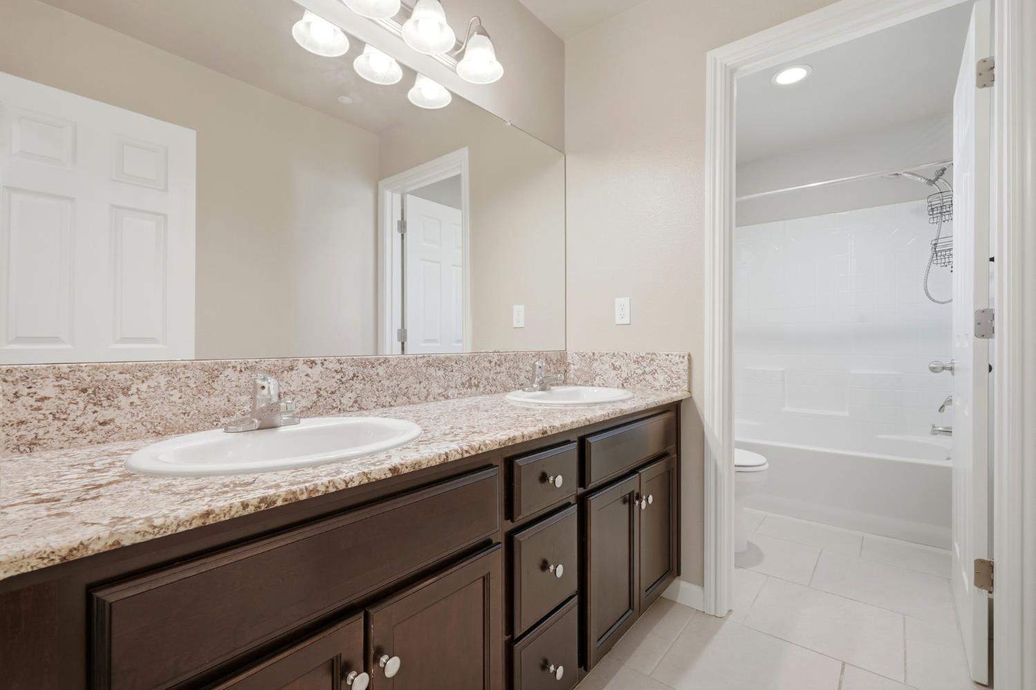 1515 Zenith Clovis, CA 93619 - Photo 28 of 41 a bathroom with a granite countertop sink a mirror and a shower