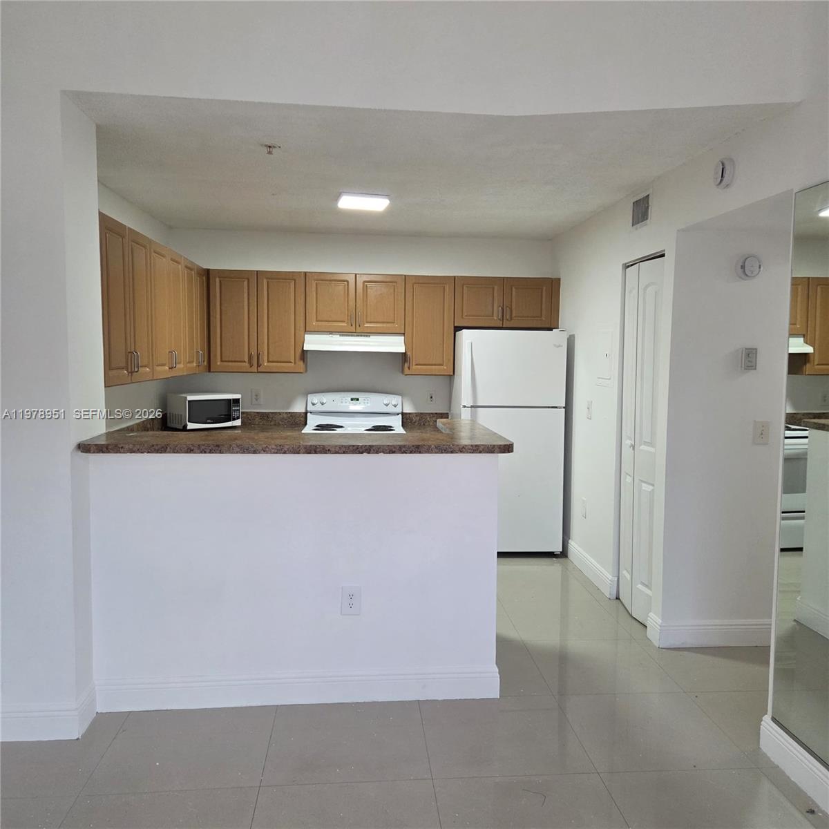 2031 Renaissance Boulevard, Unit 307 Miramar, FL 33025 - Photo 5 of 11 a kitchen with kitchen island granite countertop cabinets and refrigerator