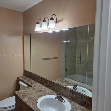 a bathroom with a granite countertop sink a mirror and shower