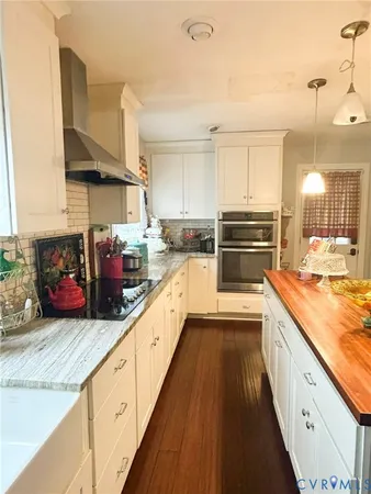 a large kitchen with stainless steel appliances granite countertop a lot of counter space and wooden floor