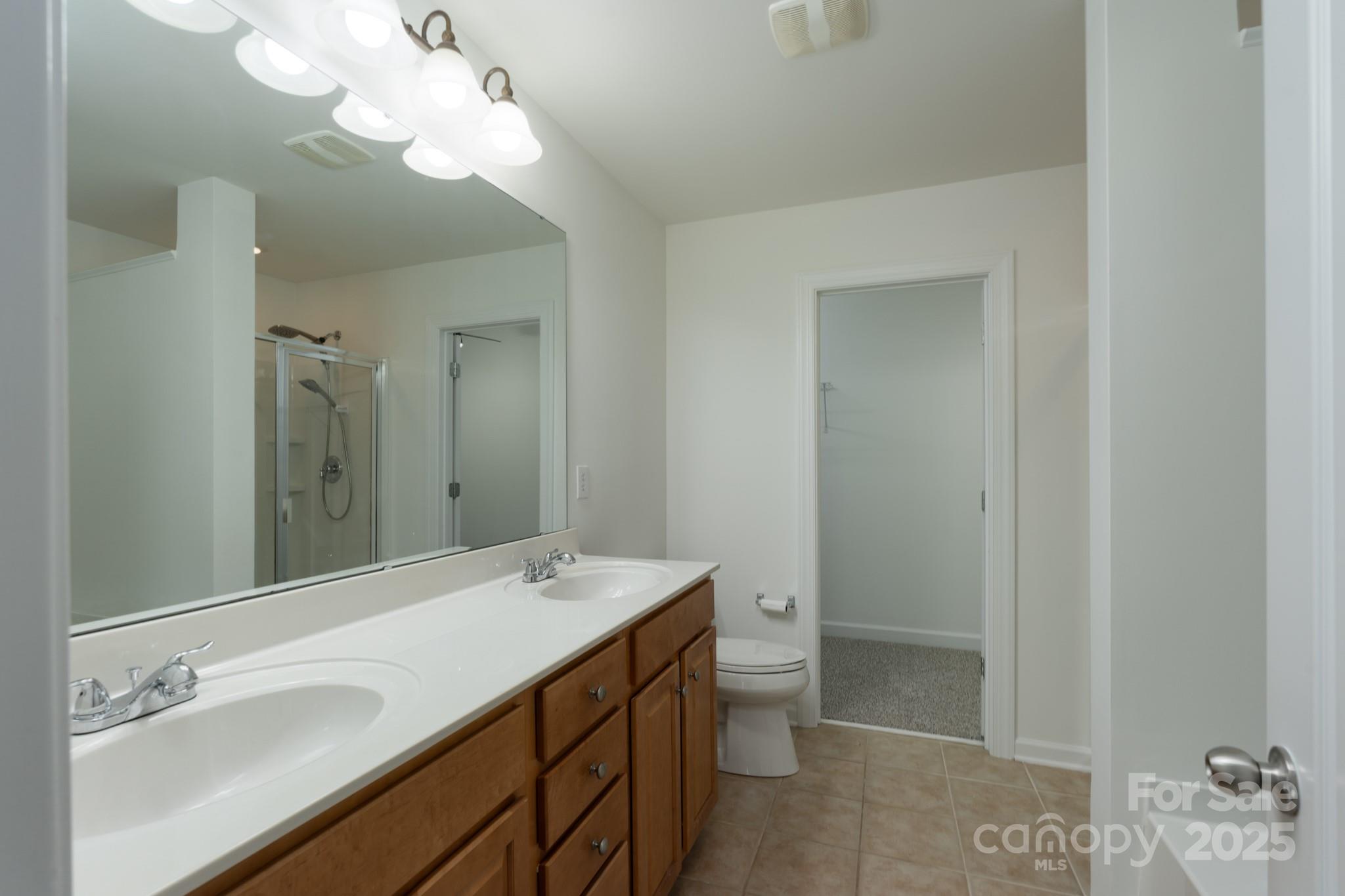 11945 Red Rust Lane Charlotte, NC 28277 - Photo 26 of 41 a bathroom with a double vanity sink a toilet and a mirror