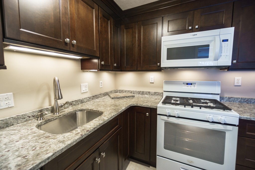 50 Colonial Drive, Unit 8 Andover, MA 01810 - Photo 4 of 25 a kitchen with granite countertop a stove top oven microwave and cabinets