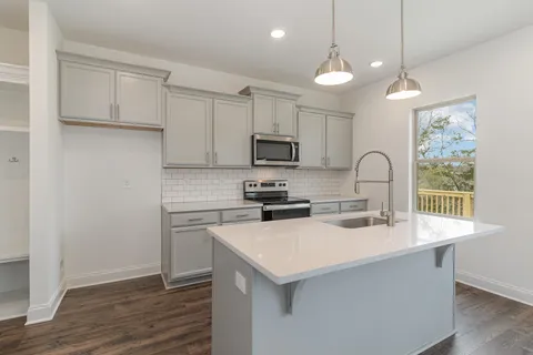 a kitchen with granite countertop a sink a counter space appliances and cabinets