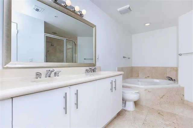 a bathroom with a granite countertop sink a toilet and a large mirror