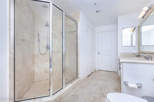 a bathroom with a shower sink mirror and toilet