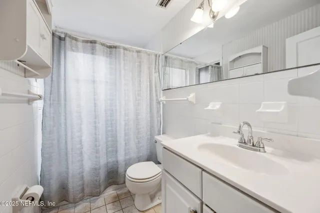 a bathroom with a sink a toilet a mirror and shower curtain