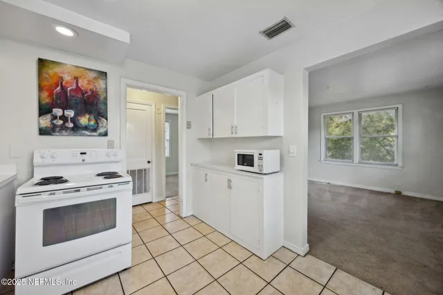 a kitchen with white cabinets a stove and a refrigerator