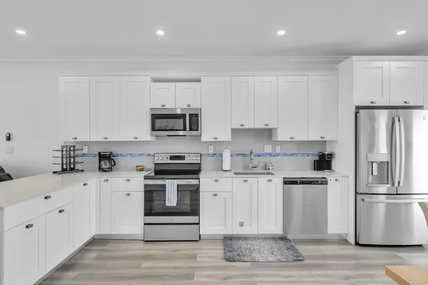 a kitchen with cabinets stainless steel appliances and wooden floor