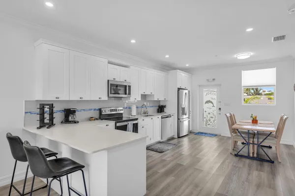 a kitchen with stainless steel appliances kitchen island granite countertop a dining table chairs and granite counter tops