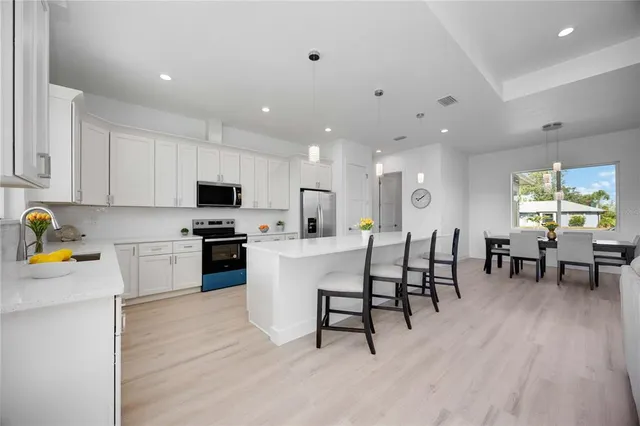a large white kitchen with wooden floors and stainless steel appliances