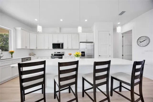 a large kitchen with stainless steel appliances kitchen island granite countertop a large stove a sink dishwasher and a microwave with wooden floor