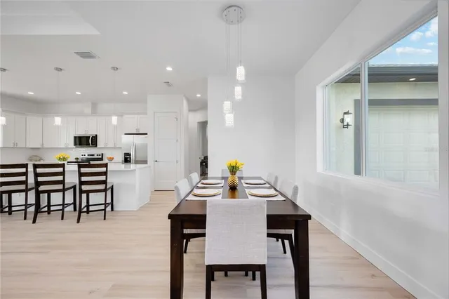 a view of a dining room and livingroom with furniture wooden floor a rug a painting and a chandelier