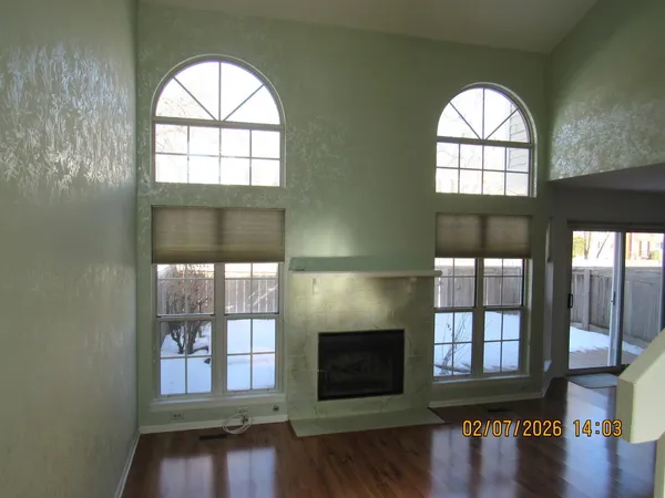 an empty room with wooden floor a fireplace and windows