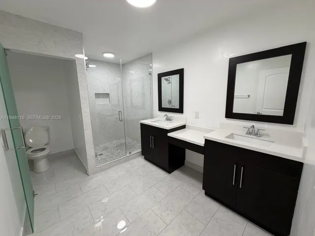 a bathroom with a double vanity sink toilet and mirror