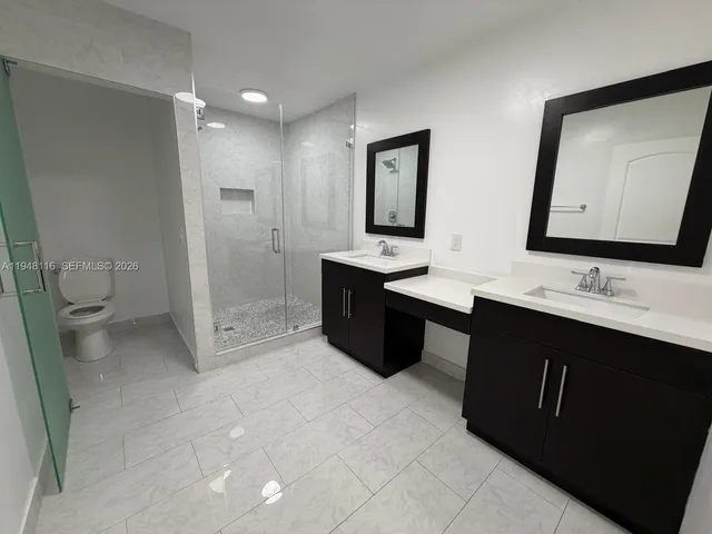 a spacious bathroom with a double vanity sink toilet and mirror