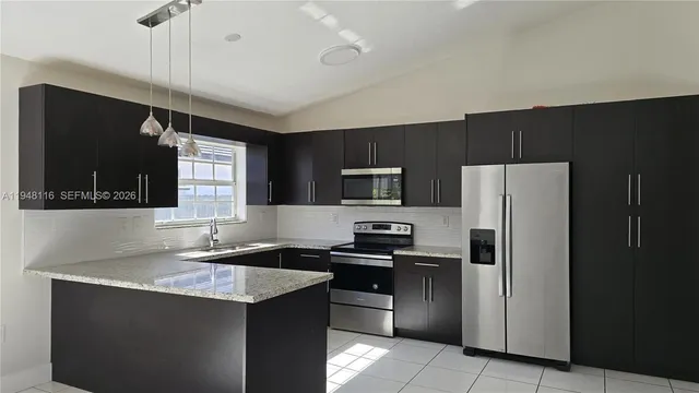 a kitchen with a refrigerator a sink a stove a microwave and wooden cabinets