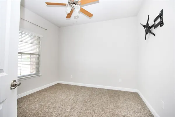 an empty room with windows and fan