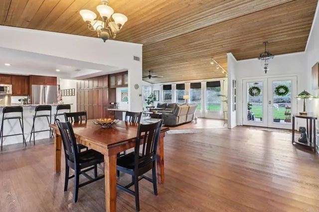a kitchen with stainless steel appliances granite countertop table chairs stove and wooden floor