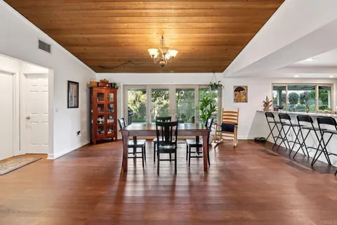 a kitchen with stainless steel appliances a dining table chairs refrigerator and wooden floor