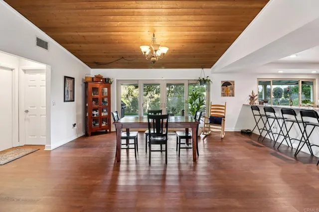 a kitchen with stainless steel appliances a dining table chairs refrigerator and wooden floor