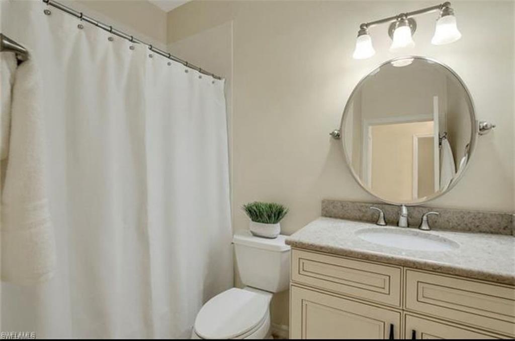 298 Emerald Bay Circle, Unit K6 Naples, FL 34110 - Photo 7 of 9 a bathroom with a granite countertop sink and a mirror